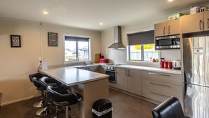 Una cocina moderna con una isla central, electrodomésticos de acero inoxidable y taburetes de bar.