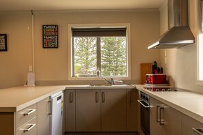 Eine moderne Küche mit großem Fenster, Edelstahlgeräten und Blick auf Bäume.