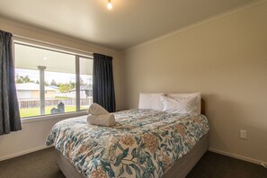 Une chambre à coucher avec un lit, une fenêtre avec des rideaux et une vue sur l’extérieur.