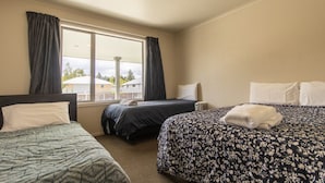 Habitación de hotel con dos camas individuales, un ventanal con cortinas y vistas al exterior.