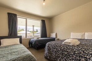 Ein Hotelzimmer mit zwei Einzelbetten, einem großen Fenster mit Vorhängen und Blick nach außen.