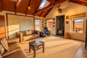 A cozy living room with a leather sofa, a coffee table, a fireplace, and a map on the wall.