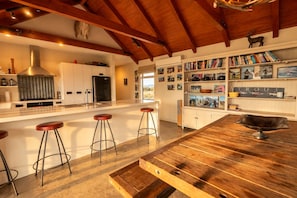 A modern kitchen with a central island, bar stools, and a wooden ceiling.