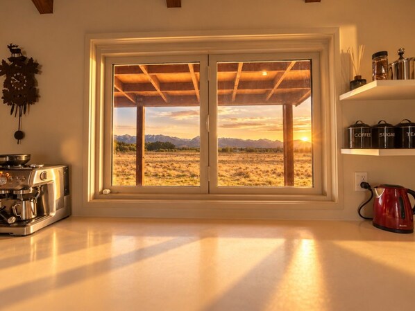 A kitchen with a large window overlooking a mountainous landscape.