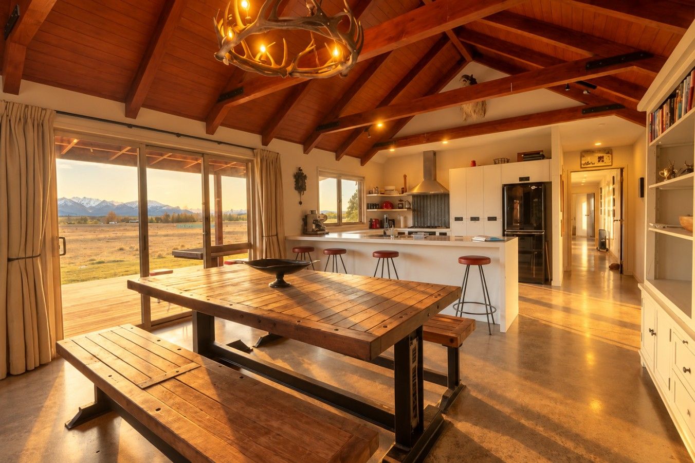 A spacious kitchen with a central island, wooden flooring, and a view of mountains through large windows.