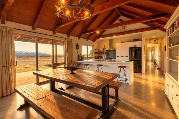 A spacious kitchen with a central island, wooden flooring, and a view of mountains through large windows.