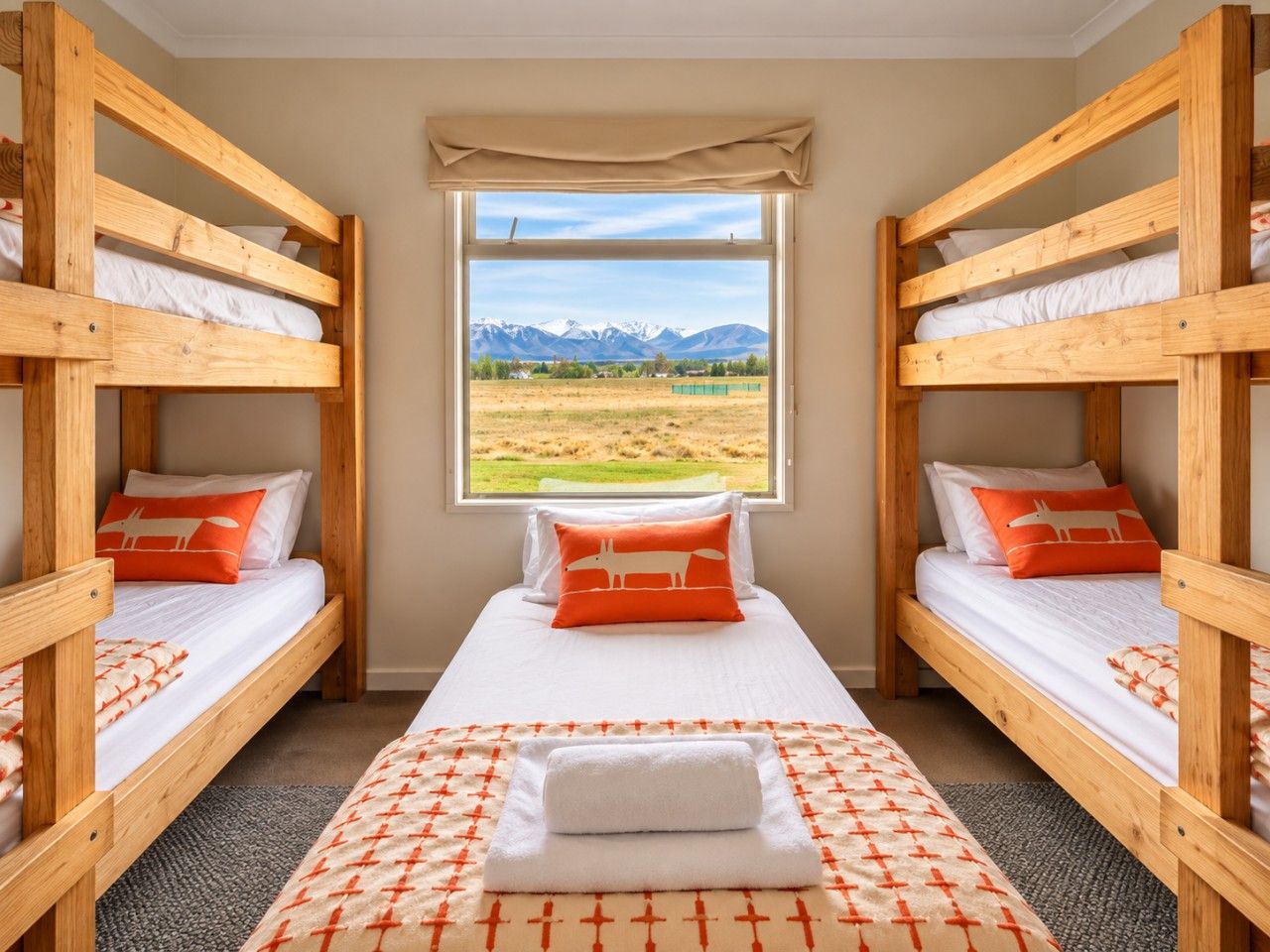 A room with two bunk beds, a window with a mountain view, and a patterned rug.