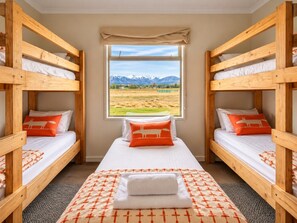 A room with two bunk beds, a window with a mountain view, and a patterned rug. - Raspberry Hut, Huge Spaces & Panoramic Views (Twizel)