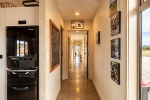 A hallway with a kitchen area on the left, featuring a black refrigerator and oven. The walls are adorned with framed artwork.