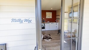 A kitchen with white cabinets, a dog lying on the floor, and a sliding glass door leading to a patio.