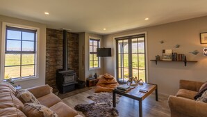 A cozy living room with a fireplace, leather sofas, a coffee table, and a bookshelf.