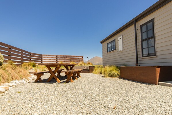 A gravel patio with picnic tables and a wooden fence.