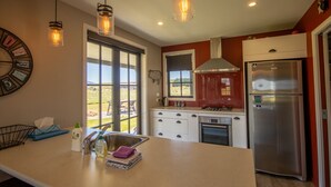 A modern kitchen with a large island, stainless steel appliances, and pendant lighting.