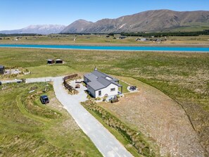 Une propriété rurale comprenant une maison, une allée et un plan d’eau en arrière-plan.