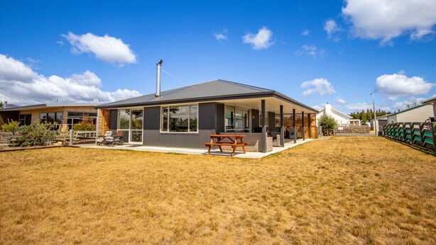 A modern house with a covered patio, a chimney, and a well-maintained lawn. - New with a View, Twizel - FREE WIFI (Twizel)