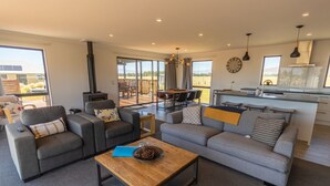 A modern living room with sofas, a coffee table, and a dining area with a view.