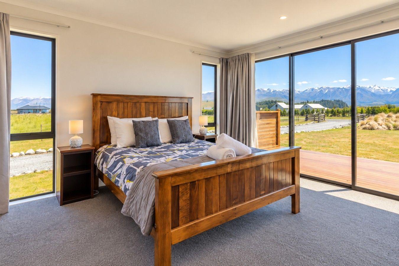 A bedroom with a wooden bed, large windows, and a view of mountains.