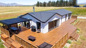 A modern house with a deck, outdoor seating, and a barbecue area.