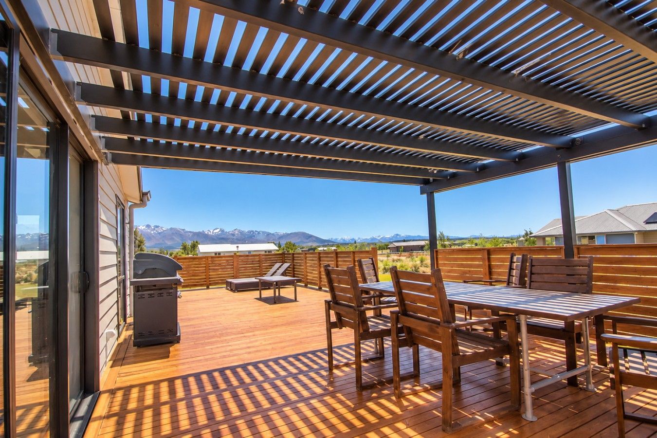 Une terrasse extérieure avec une plateforme en bois, un barbecue et une table avec des chaises.