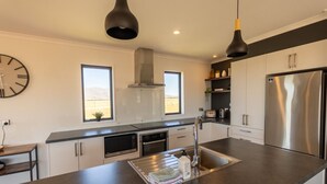A modern kitchen with a large island, stainless steel appliances, and pendant lighting.