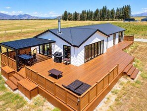 Une maison moderne dotée d’une terrasse, d’un espace salon extérieur et d’un coin barbecue.