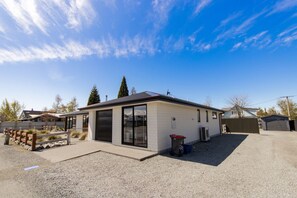 A modern single-story house with a garage, a fenced yard, and a gravel driveway. - Mackenzie Magic, Twizel - FREE WIFI (Twizel)
