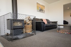 A living room with a fireplace, a sofa, and a painting on the wall. - Mackenzie Magic, Twizel - FREE WIFI (Twizel)