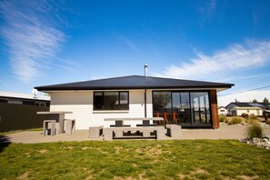A modern single-story house with a large glass door and windows, a flat roof, and a small patio area. - Mackenzie Magic, Twizel - FREE WIFI (Twizel)