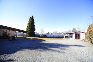 A gravel driveway leading to a building with a covered patio area and a small red-roofed structure. - Home away from Home, Twizel. FREE WIFI (Twizel)