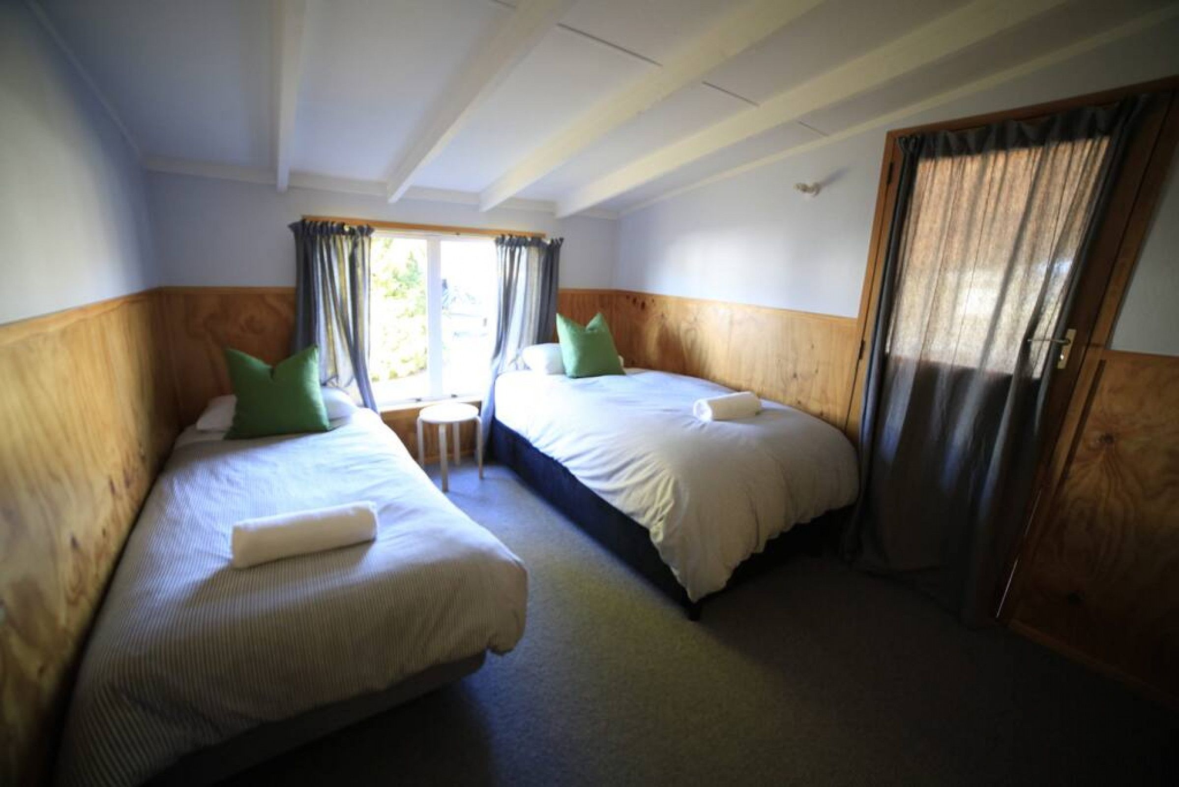 Een kamer met twee bedden, een tafeltje en een deur.