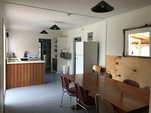 A modern kitchen with a central island, a dining area with a wooden table and chairs, and pendant lighting. - Home away from Home, Twizel. FREE WIFI (Twizel)
