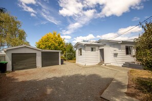 A residential area with two single-story houses, a garage, and a gravel driveway.