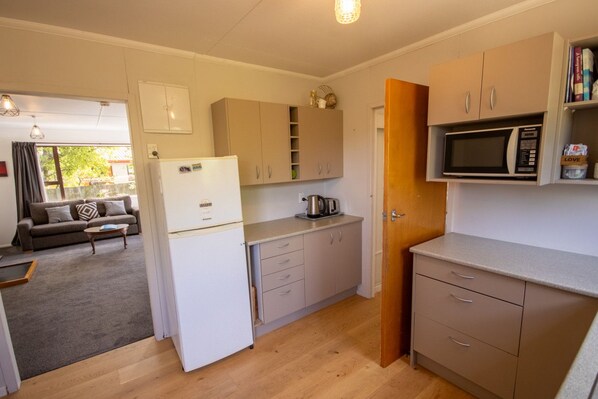 A compact kitchen with a refrigerator, microwave, and wooden cabinets.