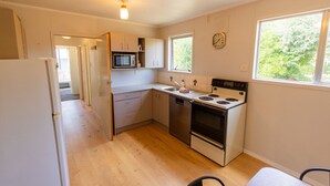 A compact kitchen with a microwave, stove, and refrigerator. - Holiday Haven - FREE WIFI (Twizel)