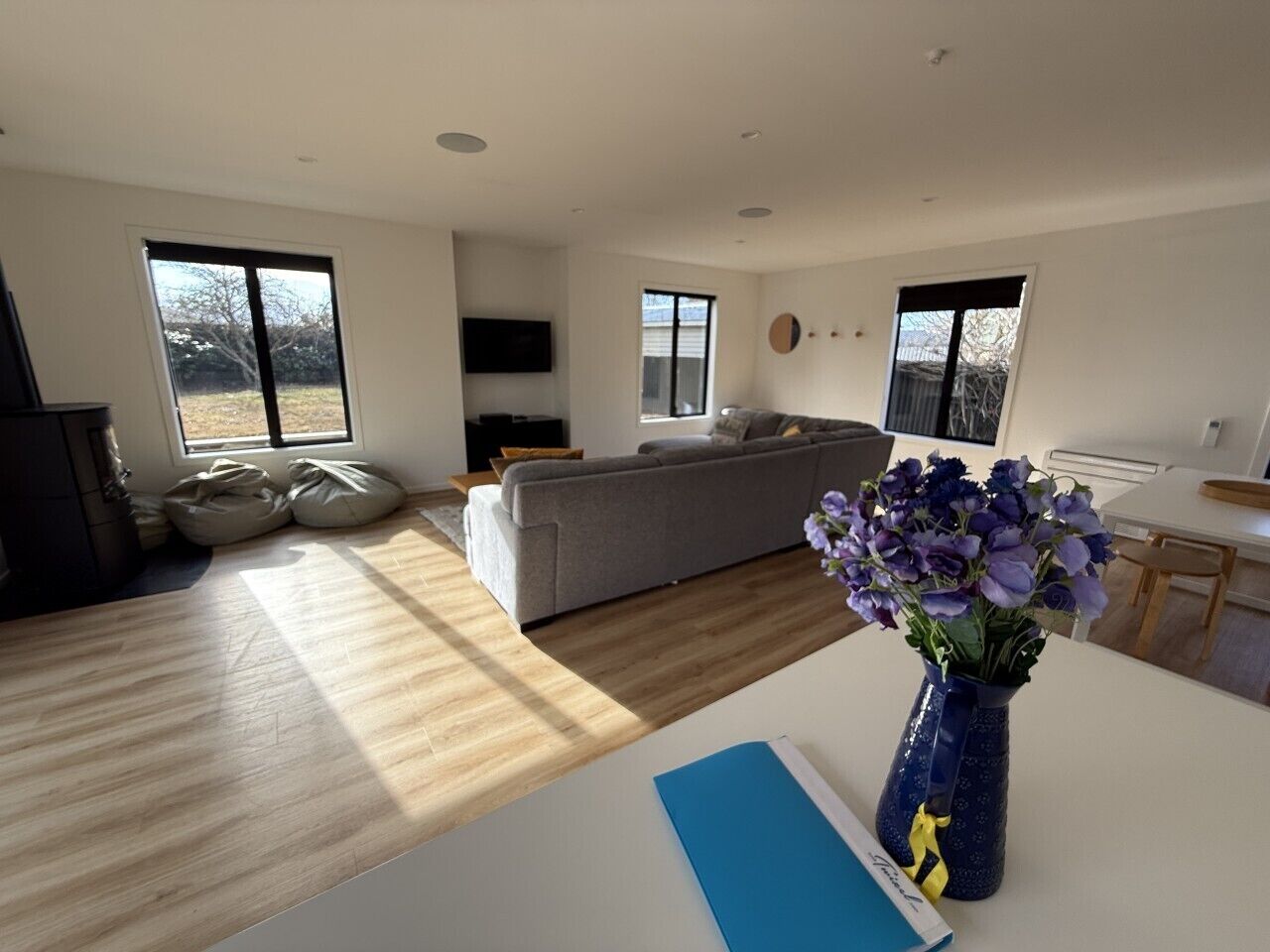 A modern living room with a sofa, a dining table, and a vase of flowers.