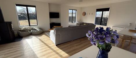 A modern living room with a sofa, a dining table, and a vase of flowers.