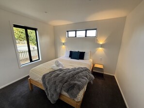 Una camera da letto con un letto, una finestra, un comodino e una lampada a parete.