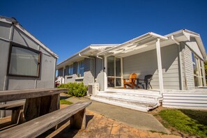 A mobile home with a porch, a wooden bench, and a table with chairs. - Fantastic Family Home on Fraser -FREE WIFI -TWIZEL (Twizel)