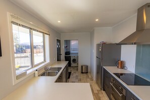 Een moderne keuken met een ingebouwde wasmachine en droger, roestvrijstalen apparatuur en een groot raam voor veel daglicht.