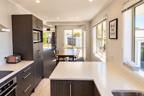 A modern kitchen with a dining area, large windows, and a view of the backyard. - Fantastic Family Home on Fraser -FREE WIFI -TWIZEL (Twizel)
