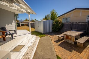 A patio area with a wooden deck, a metal shed, and a picnic table with benches. - Fantastic Family Home on Fraser -FREE WIFI -TWIZEL (Twizel)
