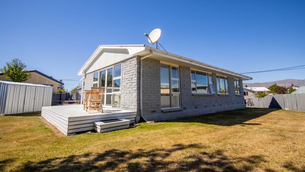 Una casa de un piso con antena parabólica, una terraza y un ventanal grande.