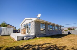 Een gelijkvloers huis met een schotelantenne, een terras en een groot raam.
