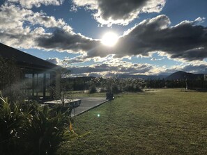 A modern house with a glass conservatory, a grassy yard, and a mountain backdrop. - Big Sky, Big View - Family friendly and close to Mt Cook, FREE WIFI (Twizel)