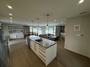 A modern kitchen with a central island, a dining area with a sofa, and large windows.