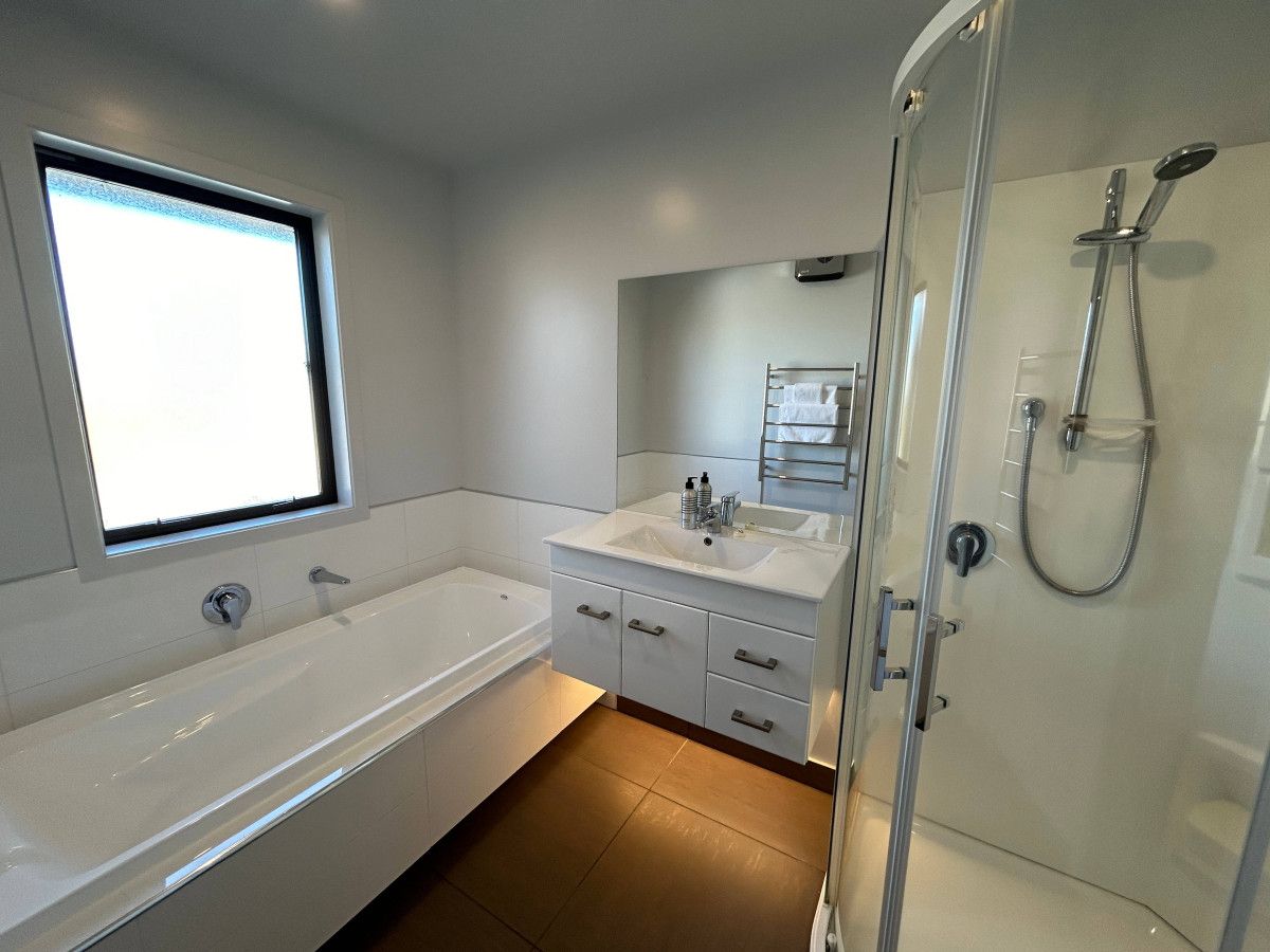 A modern bathroom with a bathtub, a shower, and a vanity with a mirror.