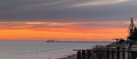 A coastal sunset view with a pier extending into the water.