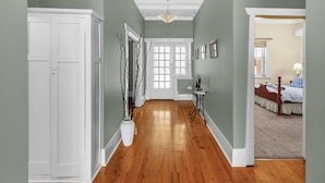 A hallway with wooden flooring, white doors, and a small table with a statue. - Adelaide Style Accommodation-City-Beach (Everard Park)