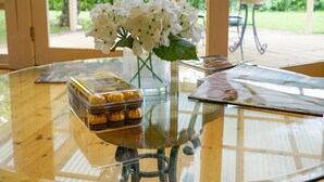 A glass-top table with a vase of white flowers, a box of chocolates, and a magazine. - Adelaide Style Accommodation-City-Beach (Everard Park)