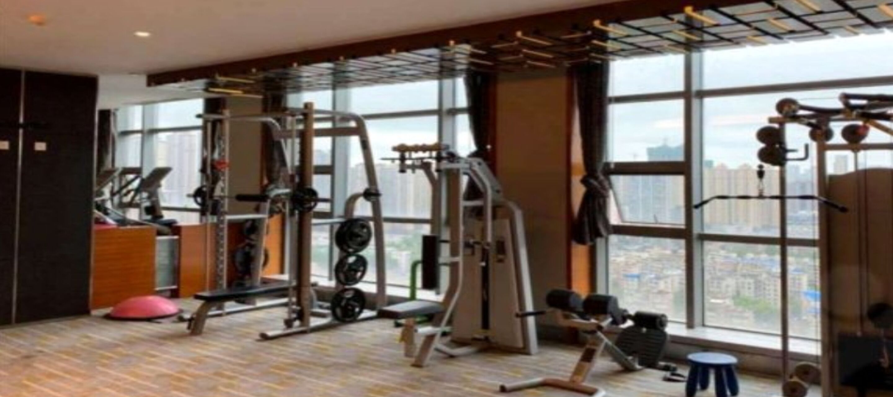 A gym with various exercise equipment, large windows, and a city view.
